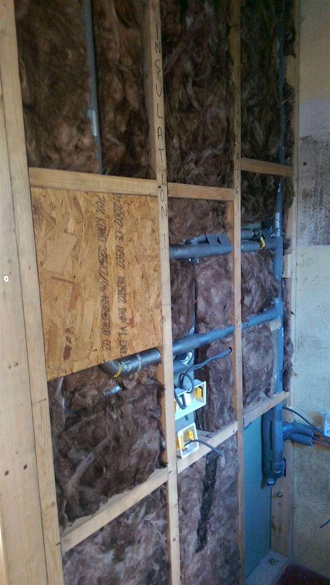 During — mineral wool insulation packed between studs alongside waste pipes and electrical back boxes